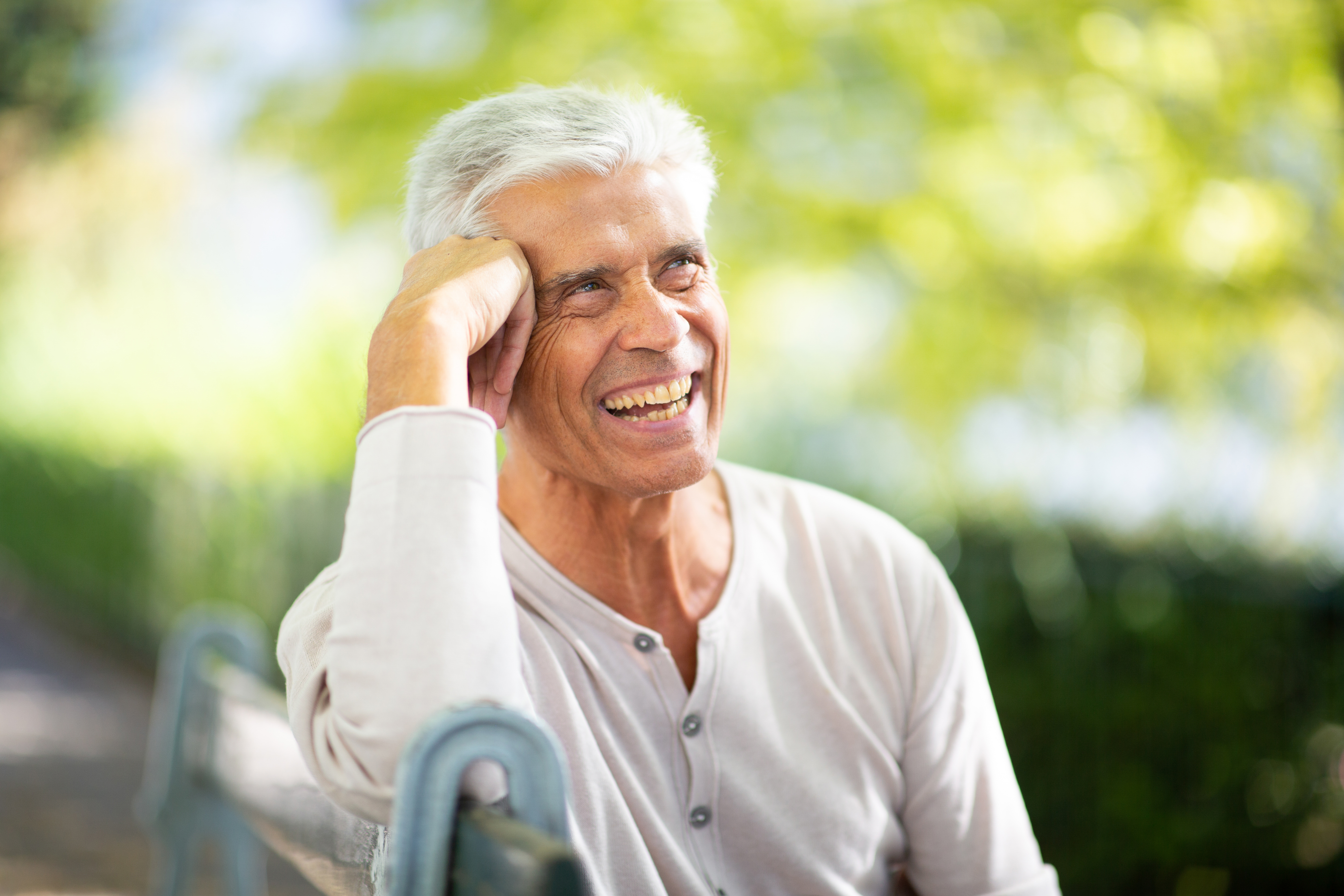 Close up handsome older man sitting on park bench and smiling