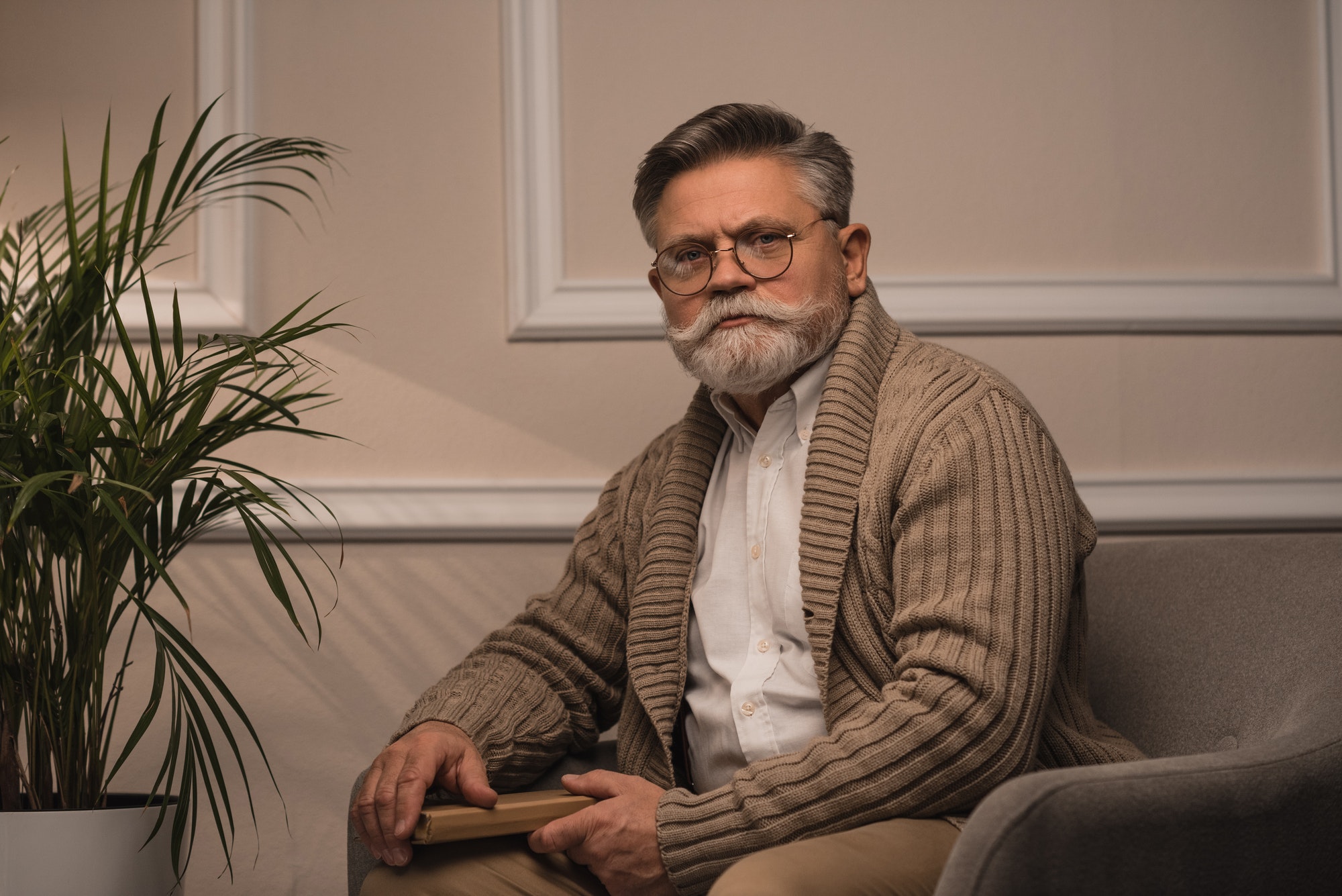 senior man sitting in cozy armchair and looking at camera