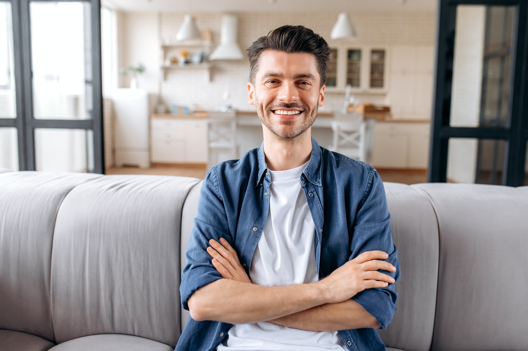 Portrait of attractive peaceful joyful young caucasian man looking at camera and smiling friendly